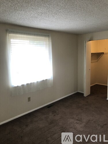 A room with a carpeted floor and a window with blinds.