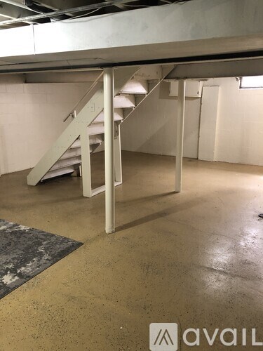 A staircase in a building with a concrete floor and a rug on the ground.