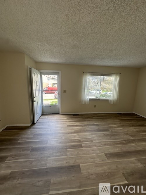 A room with wooden flooring and a window with curtains.