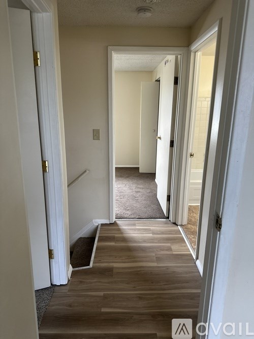 A hallway with a wooden floor and white walls.
