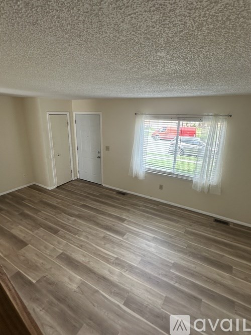 A room with wooden flooring and two doors.