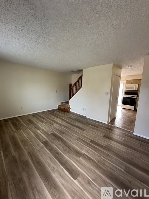 A room with wooden flooring and a staircase leading to another room.