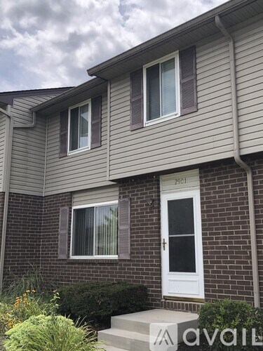 A house with a white door and windows with a sign in front.