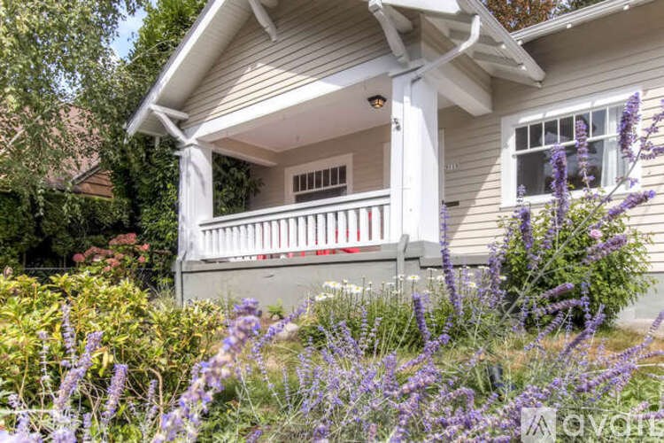 A house with a porch surrounded by purple flowers.