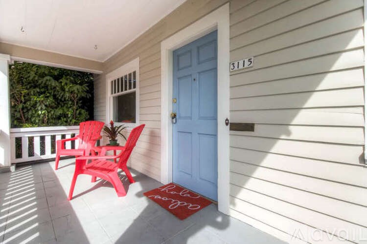 A red chair sits on a porch with a blue door.