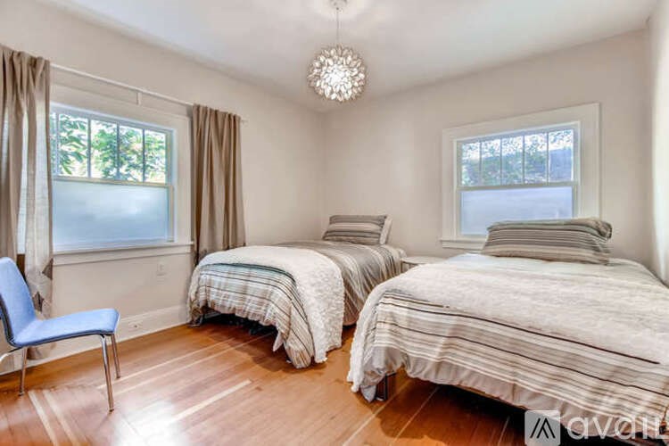 A bedroom with two beds and a blue chair.