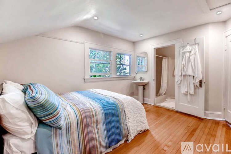A bedroom with a bed, a sink, and a window.