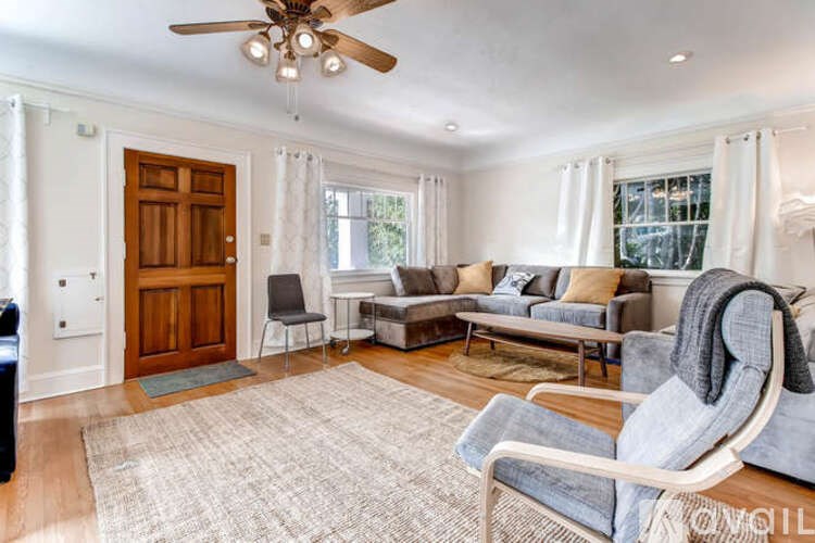 A living room with a grey chair and a brown door.