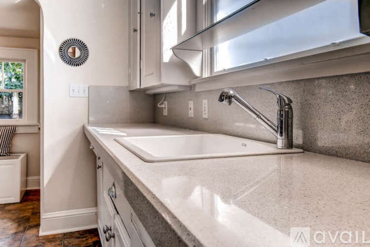 A modern kitchen with a white sink and a round decoration on the wall.