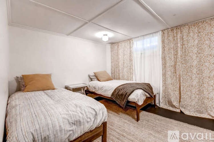 A bedroom with two beds and a nightstand.