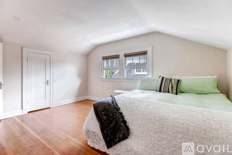 A bedroom with a bed, pillows, and a window.