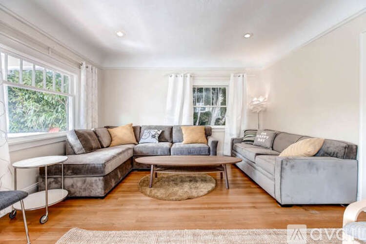 A living room with a grey couch, a white table, and a rug.