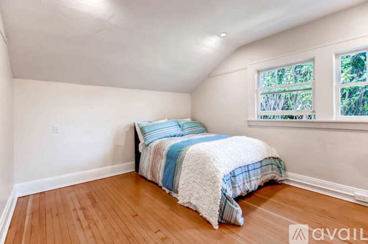 A bedroom with a bed and a window showing greenery outside.