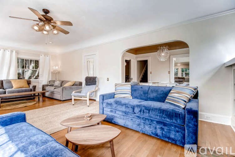 A living room with a blue velvet couch and a wooden coffee table.