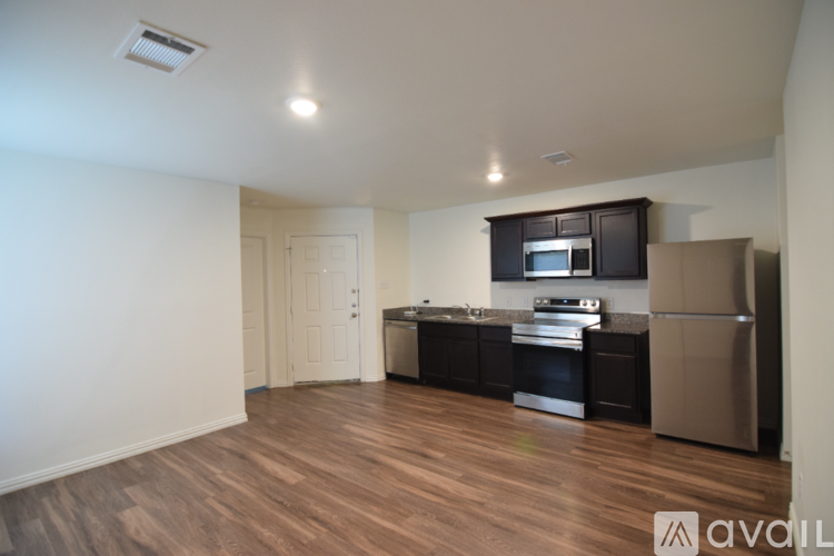A kitchen with black cabinets and stainless steel appliances in a room with wooden floors.
