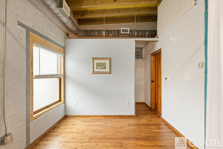 A room with wooden floors and a window on the left side.