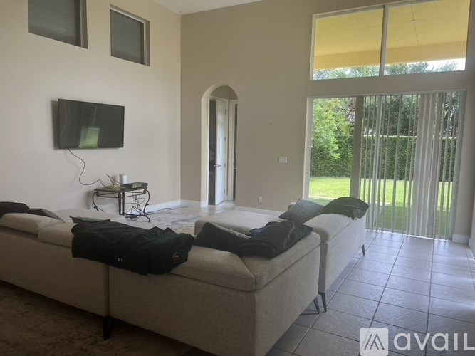 A bedroom with a bed, a television, and a sliding glass door leading to a garden.