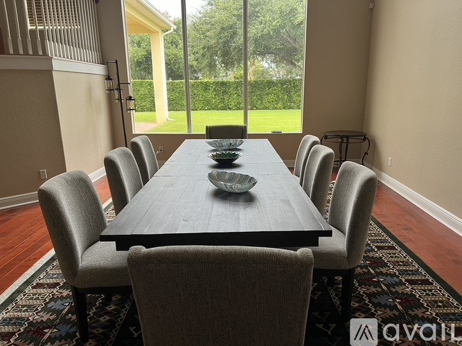 A long wooden table with a bowl on it and chairs around it.