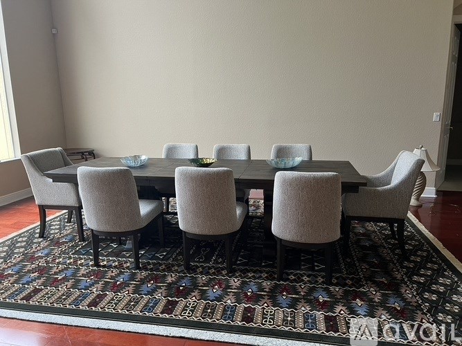 A dining table surrounded by chairs and a patterned rug.