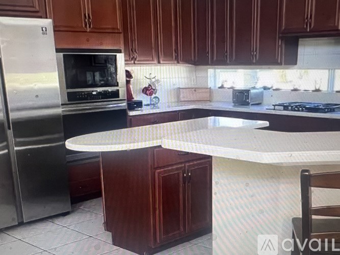 A kitchen with a refrigerator, oven, and a counter.