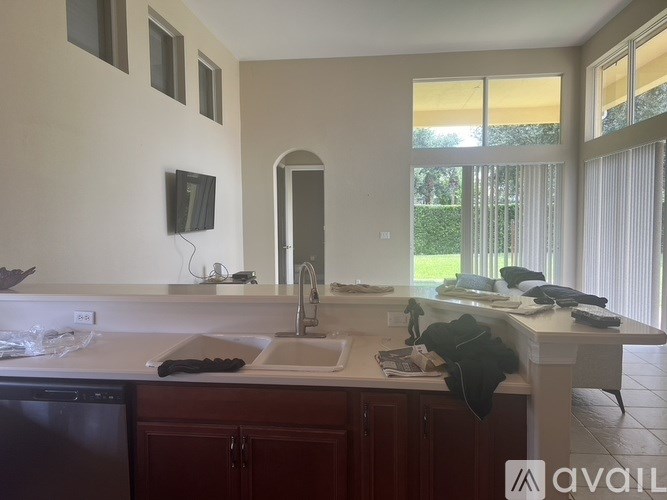 A kitchen with a sink, a dishwasher, and a counter with a black towel on it.