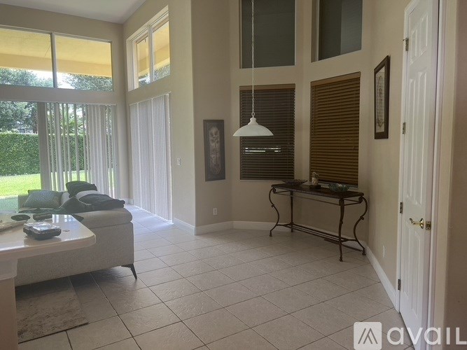 A living room with a white couch and a table with a lamp on it.