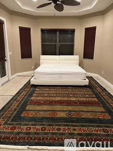 A bedroom with a large bed and a rug on the floor.