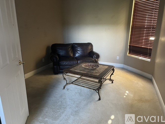 A black leather couch sits in a room with a coffee table in front of it.