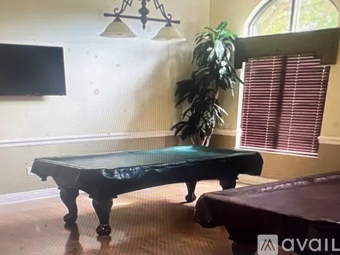 A black piano with a green cover sits in a room with a plant and a chandelier.