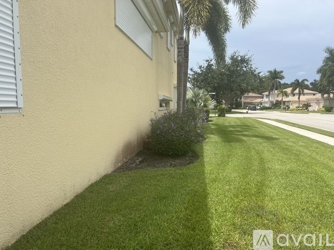 A house with a well-maintained lawn and a palm tree in the background.