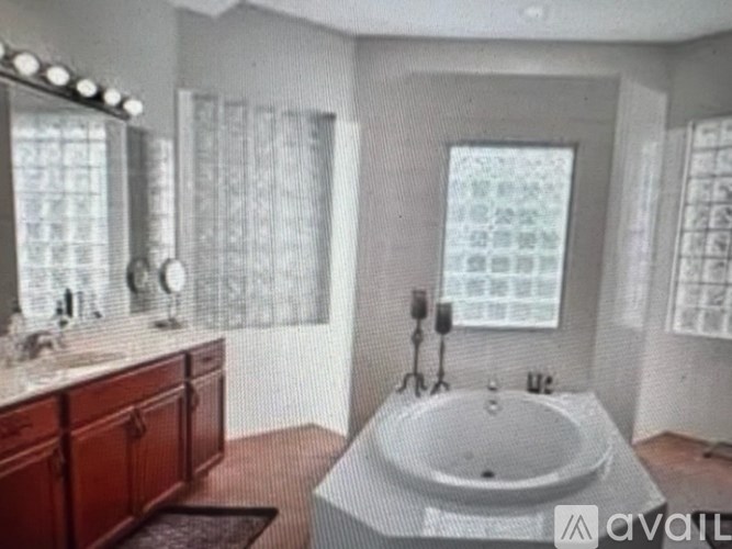 A bathroom with a large tub and a vanity with a mirror.