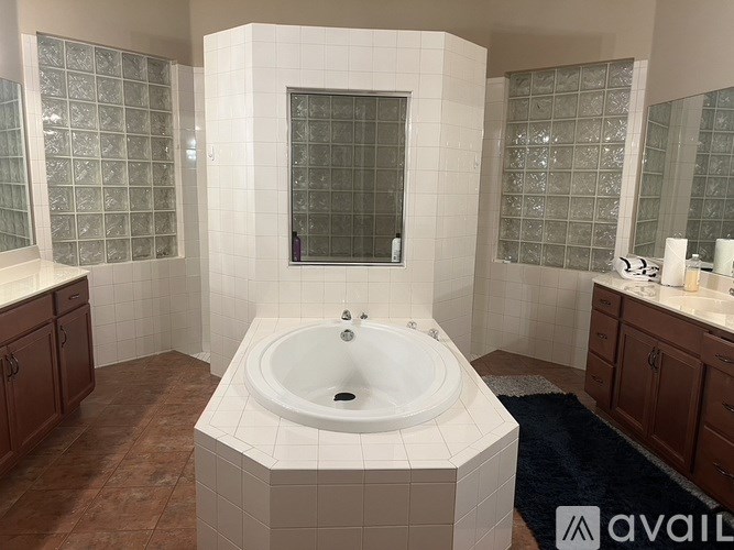 A bathroom with a white tiled tub and brown cabinets.