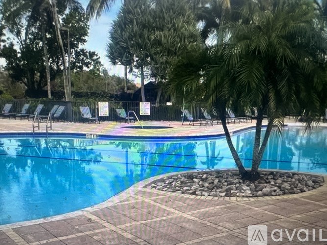 A pool surrounded by palm trees and a fence.