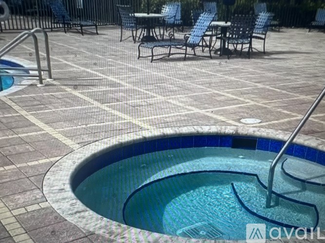 A round pool with a metal ladder is surrounded by chairs and tables.