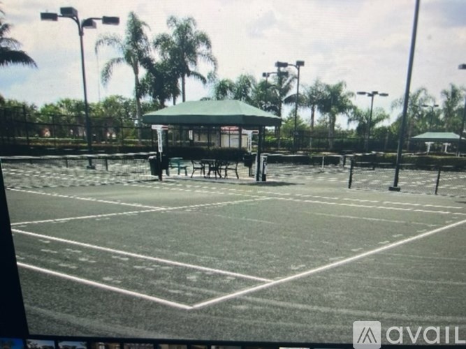 A tennis court with a green roofed pavilion and a white line marking the court.