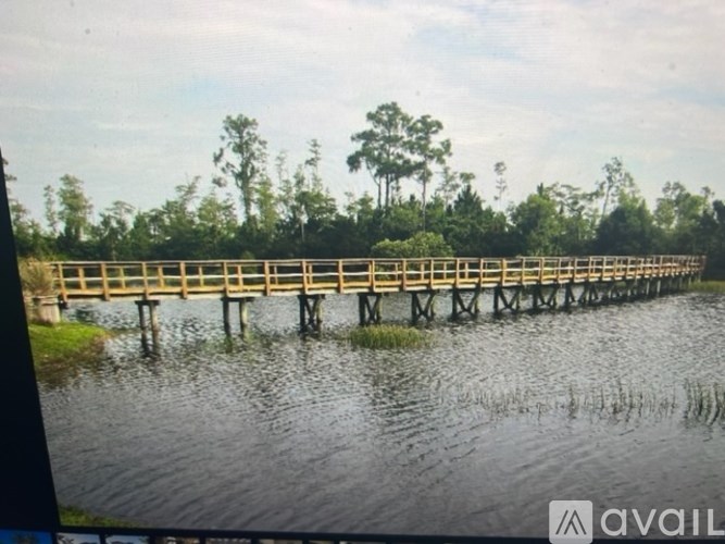 A wooden bridge over a body of water with trees in the background.