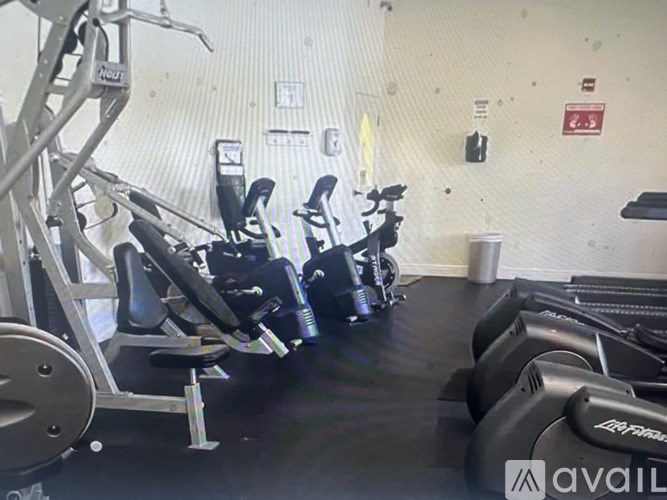 A gym with a row of exercise bikes and a weight bench.