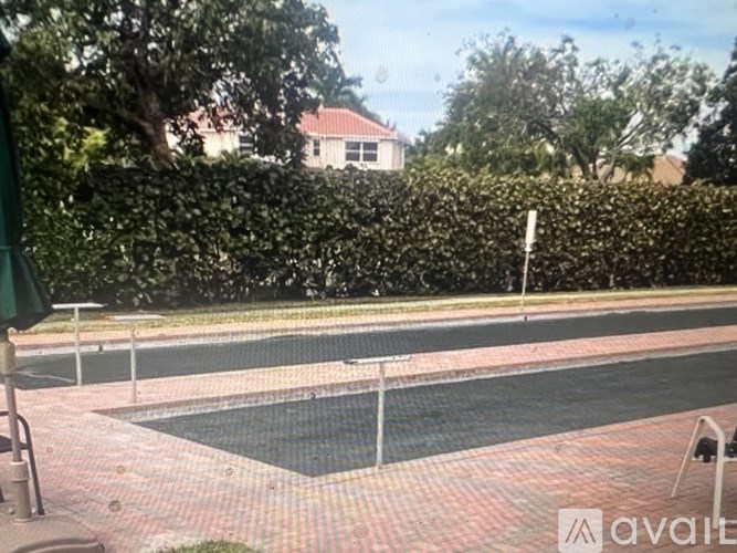 A pool surrounded by a brick border and a green umbrella.