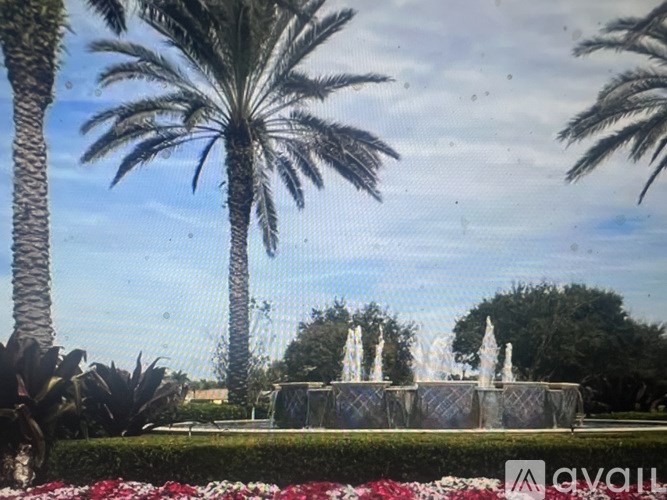 A fountain surrounded by a metal fence and a hedge.