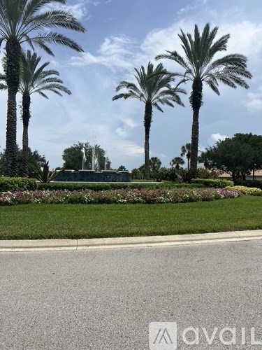 Three palm trees are in the foreground of a well-manicured lawn.