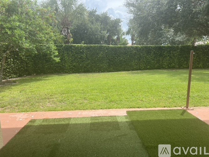 A well-maintained lawn with a hedge and a wooden post in the foreground.