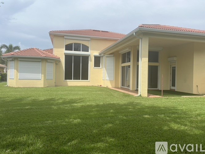 A house with a red roof and a large lawn in front.