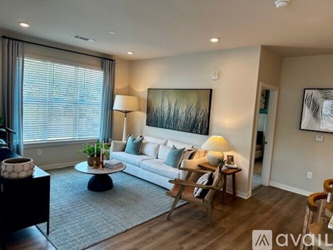 A living room with a white couch, a coffee table, and a painting on the wall.