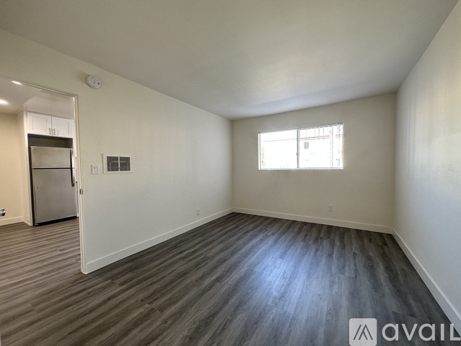 A spacious room with wooden flooring and a window.