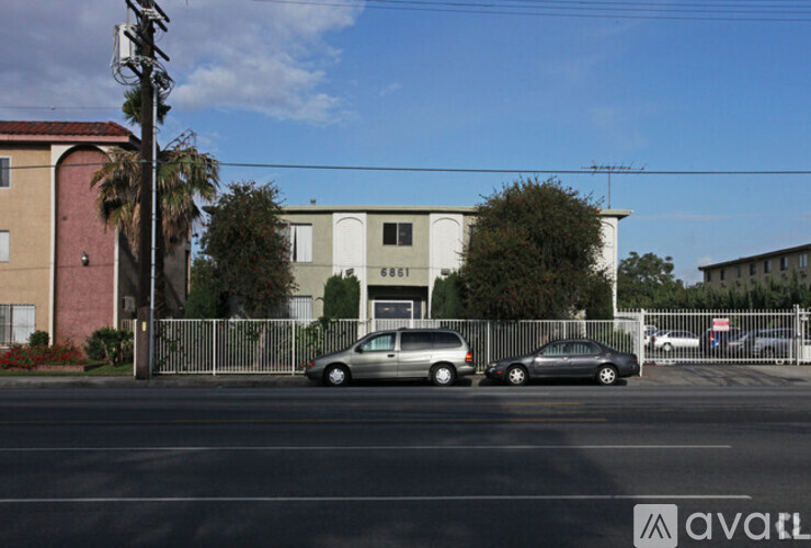 Two cars parked in front of a building with a fence.