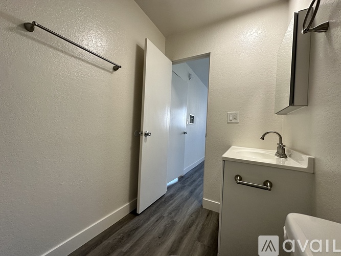 A bathroom with a sink, mirror, and a door.
