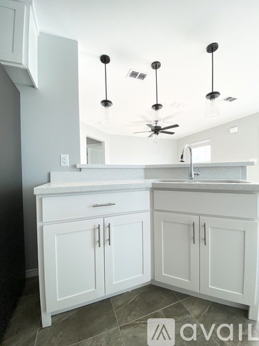 A kitchen with white cabinets and a ceiling fan.