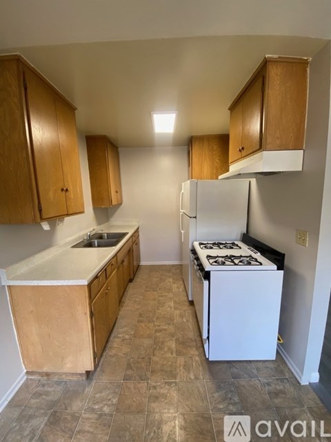 A kitchen with wooden cabinets and a white stove top oven.