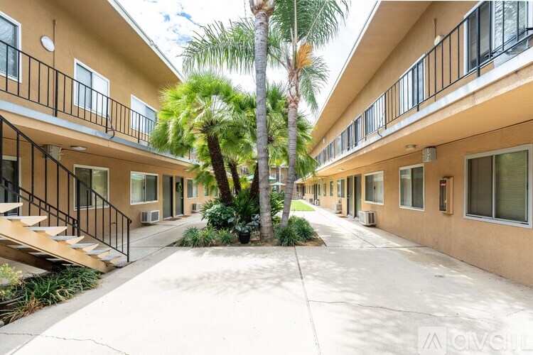 A row of apartment buildings with balconies and a palm tree in the courtyard.