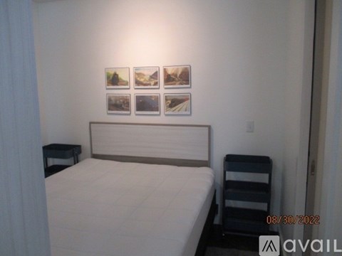 A bedroom with a bed, nightstand, and pictures on the wall.